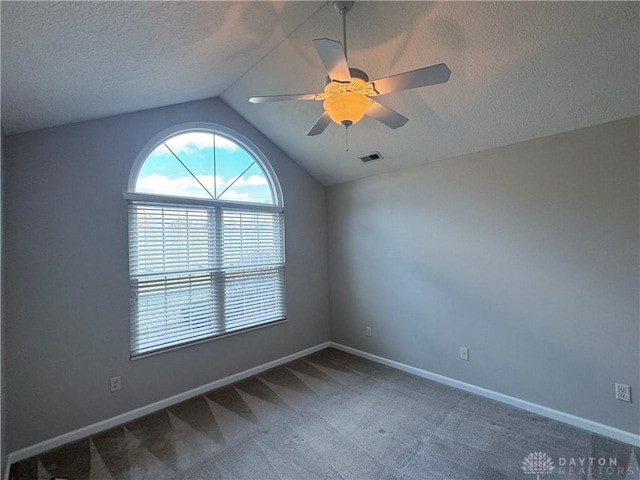 carpeted spare room with lofted ceiling, a ceiling fan, baseboards, and a textured ceiling