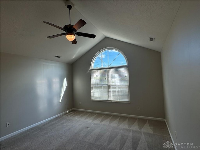 spare room featuring baseboards, lofted ceiling, a textured ceiling, and carpet flooring