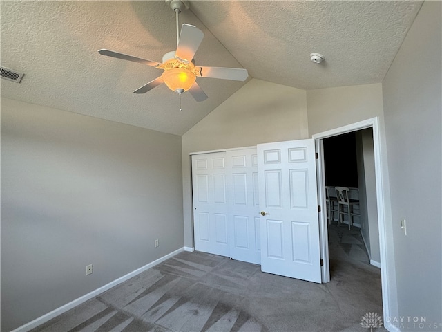 unfurnished bedroom with a textured ceiling, dark carpet, vaulted ceiling, and a closet