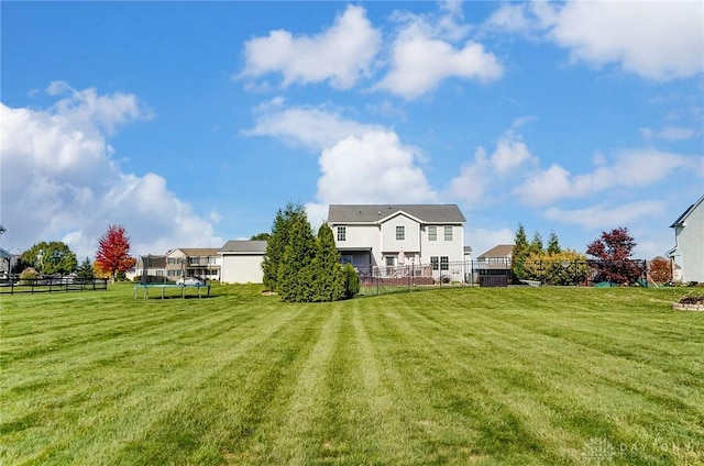 back of property featuring a trampoline and a yard