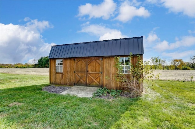 view of outdoor structure featuring a rural view and a lawn