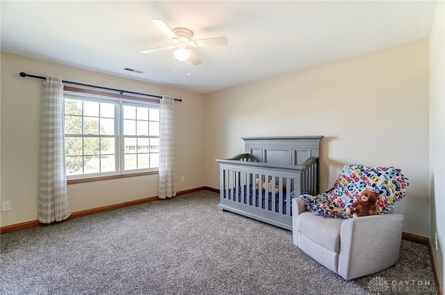 carpeted bedroom featuring a crib and ceiling fan