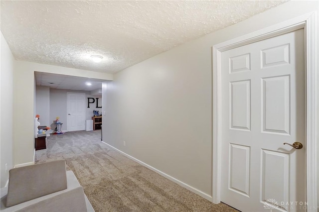 hall featuring a textured ceiling and light carpet