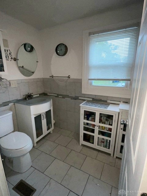 bathroom featuring vanity, tile walls, toilet, and tile patterned flooring