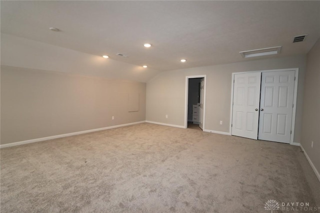 carpeted spare room with vaulted ceiling