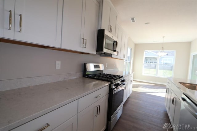 kitchen with dark hardwood / wood-style floors, white cabinetry, stainless steel appliances, and decorative light fixtures