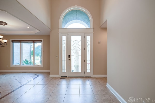 foyer entrance featuring a notable chandelier, a towering ceiling, and light tile patterned floors