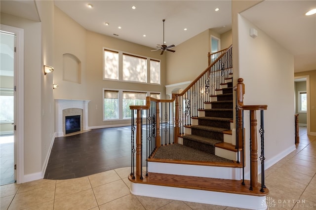 staircase with tile patterned floors, a high ceiling, and ceiling fan