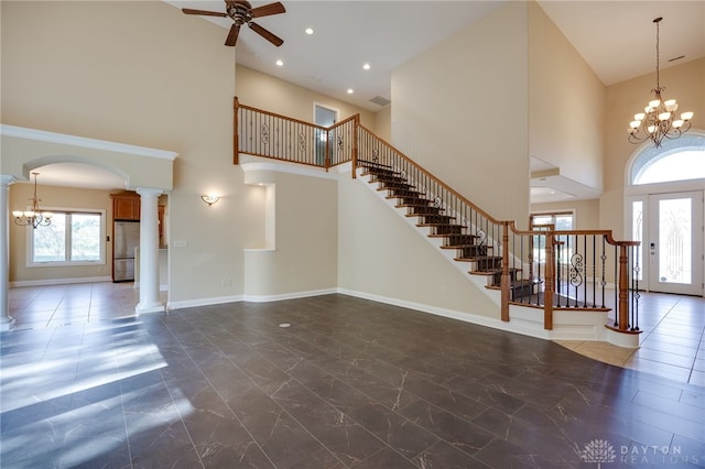 foyer featuring decorative columns, a high ceiling, and ceiling fan with notable chandelier