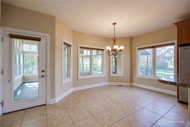 unfurnished dining area featuring an inviting chandelier and light tile patterned floors