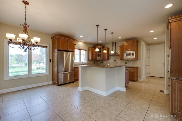 kitchen featuring backsplash, appliances with stainless steel finishes, a chandelier, pendant lighting, and wall chimney exhaust hood