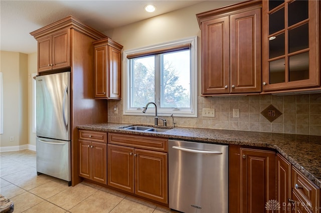 kitchen with stainless steel appliances, backsplash, dark stone counters, sink, and light tile patterned flooring