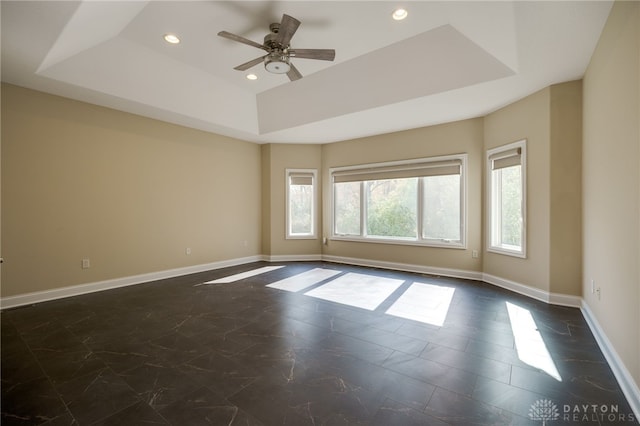 spare room featuring ceiling fan and a raised ceiling