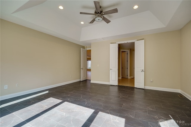 empty room featuring a tray ceiling and ceiling fan