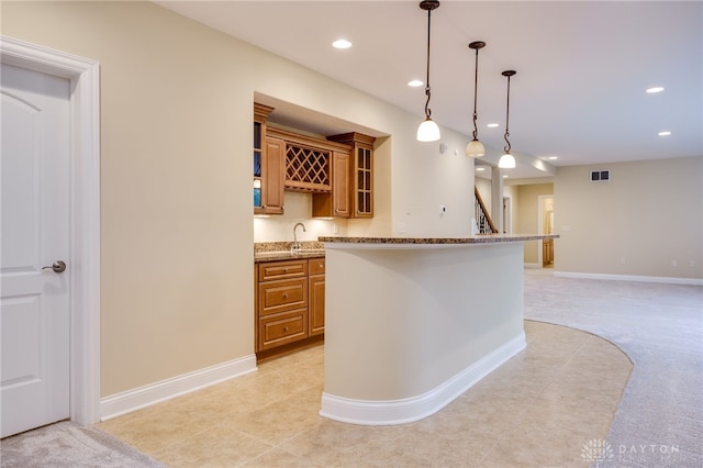 kitchen featuring light carpet, decorative light fixtures, sink, and light stone counters