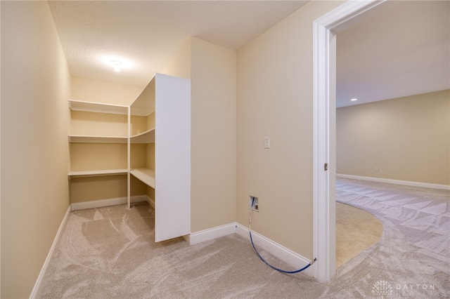 washroom with light carpet, hookup for a washing machine, and a textured ceiling