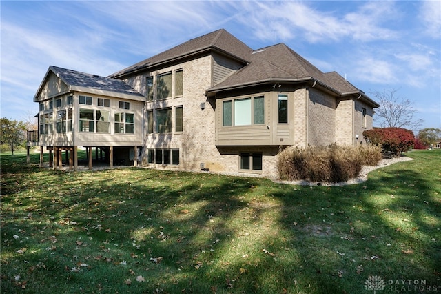 rear view of house featuring a yard and a sunroom