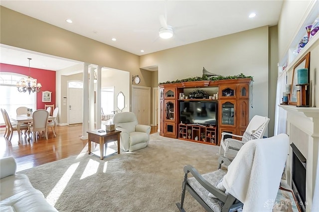 carpeted living room with ceiling fan with notable chandelier