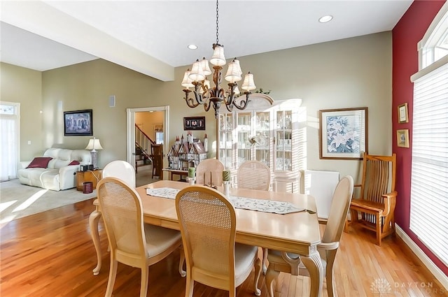 dining area with light hardwood / wood-style floors and a notable chandelier