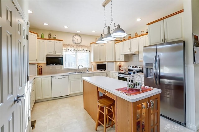 kitchen with pendant lighting, sink, appliances with stainless steel finishes, tasteful backsplash, and a kitchen island