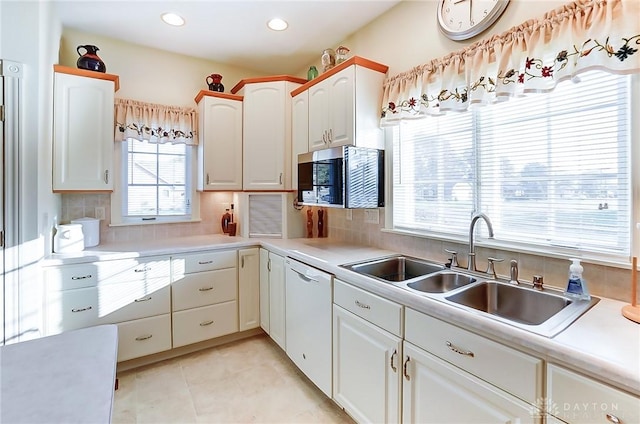 kitchen featuring backsplash, sink, dishwasher, white cabinetry, and light tile patterned flooring