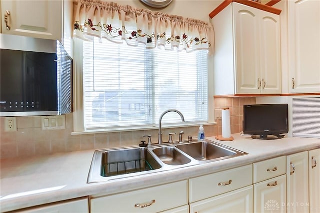 kitchen with white cabinets, backsplash, and sink