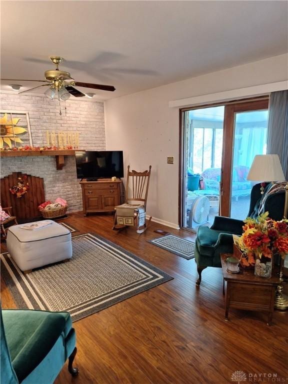 living room with ceiling fan, hardwood / wood-style flooring, brick wall, and a brick fireplace