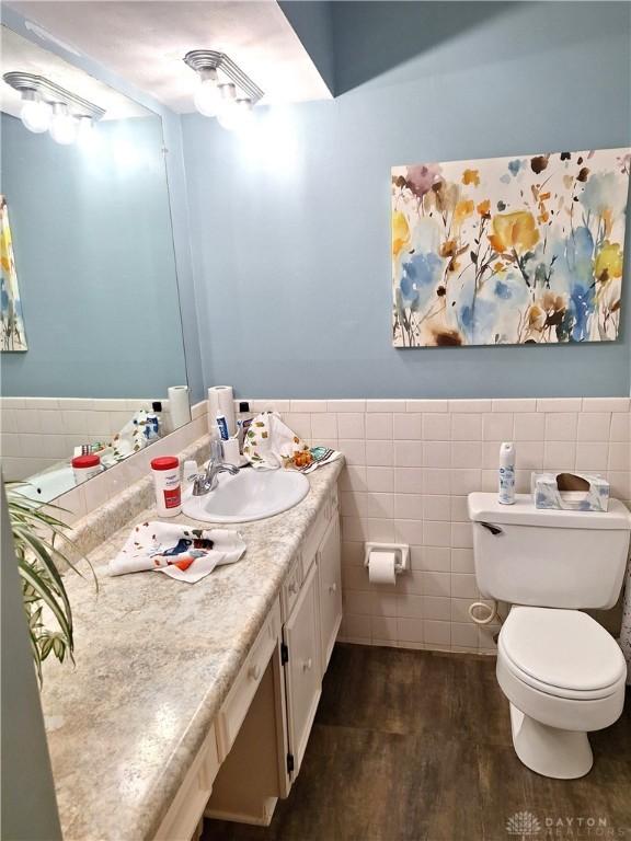 bathroom featuring vanity, hardwood / wood-style flooring, tile walls, and toilet