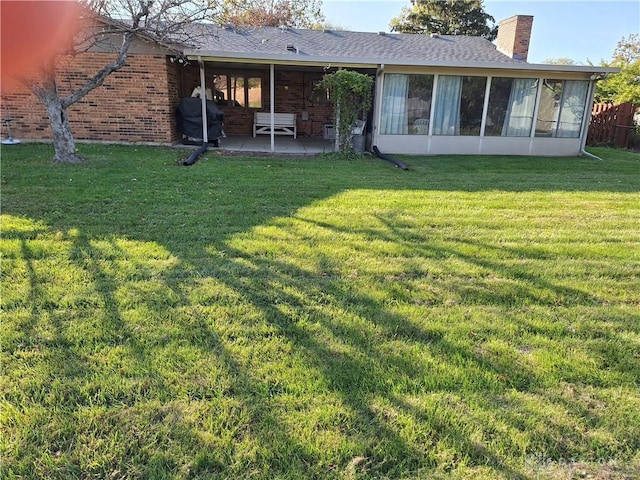 rear view of property with a sunroom, a yard, and a patio