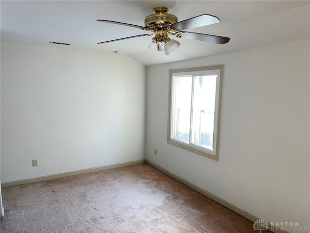 empty room featuring light carpet, vaulted ceiling, and ceiling fan