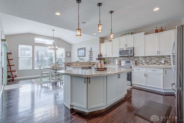 kitchen featuring stainless steel appliances, vaulted ceiling, white cabinets, hanging light fixtures, and dark hardwood / wood-style floors