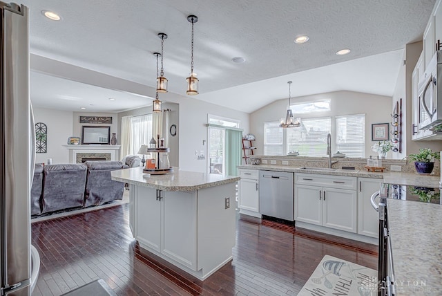 kitchen featuring white cabinets, vaulted ceiling, decorative light fixtures, and appliances with stainless steel finishes