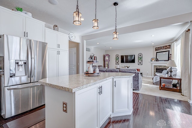 kitchen featuring stainless steel fridge with ice dispenser, dark hardwood / wood-style flooring, hanging light fixtures, white cabinets, and a center island