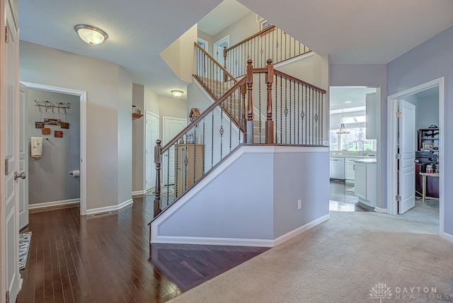 stairway with hardwood / wood-style flooring and a notable chandelier