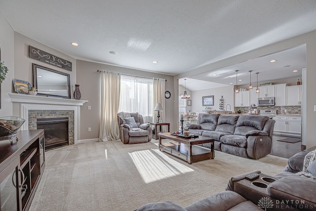 living room featuring light colored carpet, vaulted ceiling, a textured ceiling, sink, and a fireplace