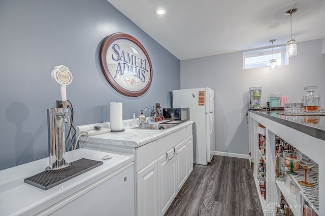 kitchen with white fridge, white cabinetry, dark hardwood / wood-style floors, hanging light fixtures, and sink