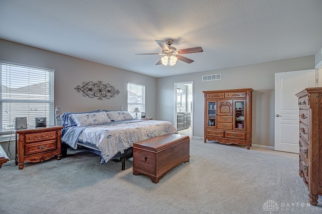 carpeted bedroom with ensuite bathroom, a textured ceiling, and ceiling fan