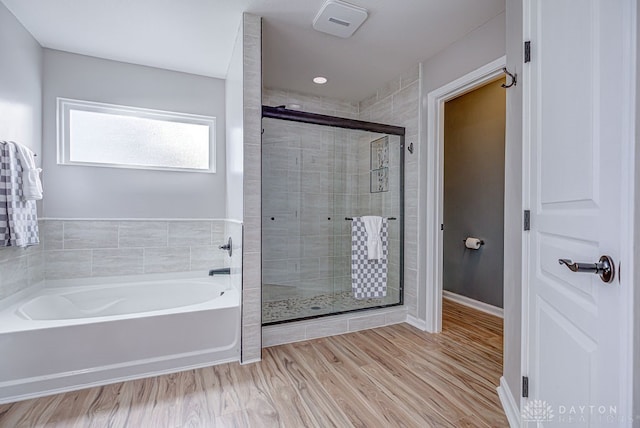 bathroom featuring plus walk in shower and hardwood / wood-style flooring