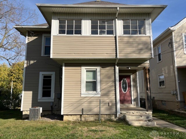 view of front of house with a front yard and cooling unit