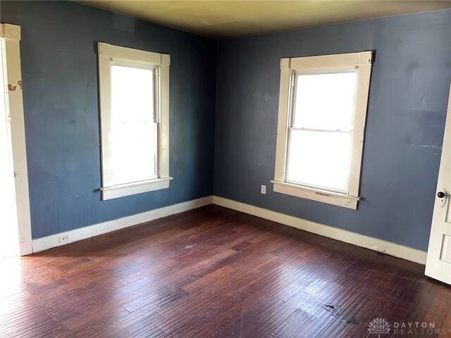 empty room with dark wood-type flooring and a wealth of natural light