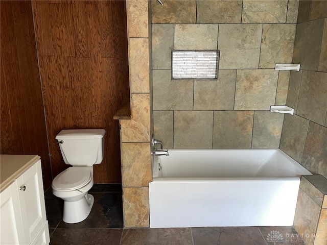 bathroom with vanity, wooden walls, toilet, and a bathing tub