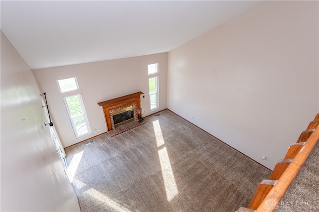 unfurnished living room with vaulted ceiling, a brick fireplace, and carpet flooring