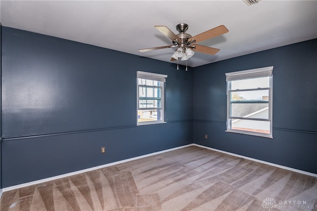 carpeted spare room with ceiling fan and plenty of natural light