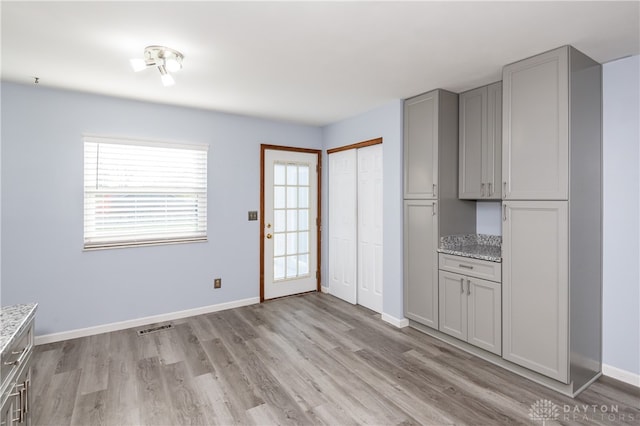 kitchen featuring light stone countertops, gray cabinetry, and light wood-type flooring