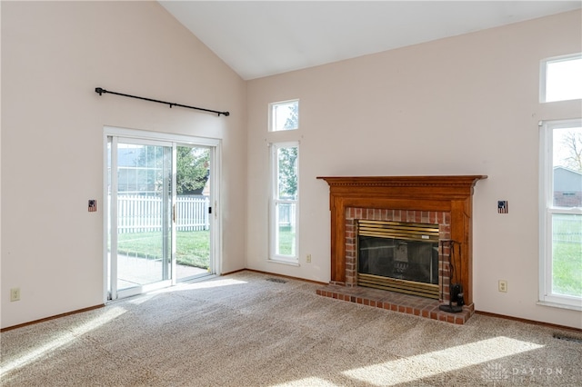 unfurnished living room featuring a wealth of natural light, a brick fireplace, carpet flooring, and high vaulted ceiling