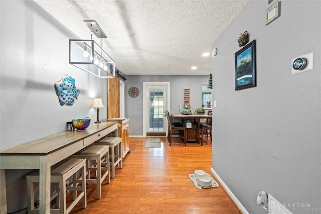 hallway featuring light hardwood / wood-style floors and a textured ceiling