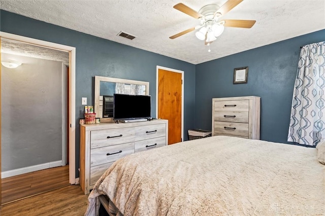 bedroom with ceiling fan, a textured ceiling, and hardwood / wood-style flooring