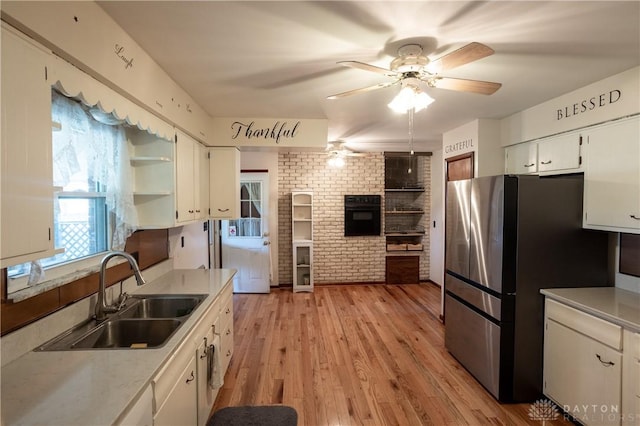 kitchen featuring white cabinetry, stainless steel fridge, sink, and light hardwood / wood-style flooring