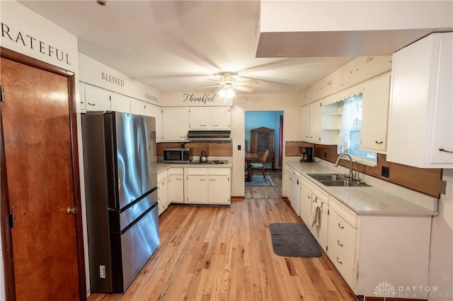 kitchen featuring ceiling fan, sink, appliances with stainless steel finishes, white cabinets, and light wood-type flooring