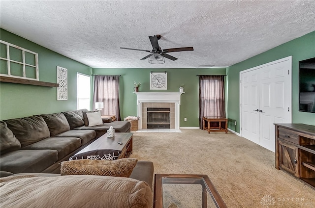 living room with carpet flooring, a tile fireplace, ceiling fan, and a textured ceiling